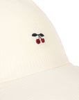 Close-up of a beige garment with embroidered cherries on a white background