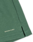 Close-up of a green fabric with 'Konges Slojd' branding on a white background