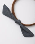 A brown fabric headband with a knotted bow in a textured dark gray fabric, shown on a plain white background.