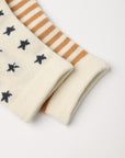 Close-up of a pair of cream knit socks folded on a white background. One sock has small dark gray star-like motifs, and the other has alternating cream and tan stripes.