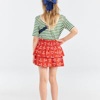 Person wearing a green and white striped shirt with a red skirt featuring anchor patterns on a white background