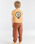Child wearing a yellow t-shirt with a lion graphic and brown pants on a white background