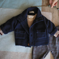 Navy coat and plaid pants on a wooden table