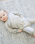 Baby lying on a textured rug wearing a patterned outfit
