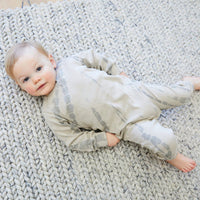Baby lying on a textured rug wearing a patterned outfit
