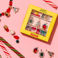 Colorful jewelry set with 'Super Smalls' packaging on a pink background