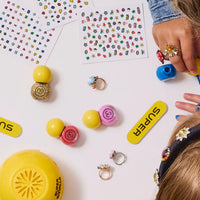 Children playing with colorful rings and stamps on a white surface
