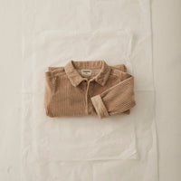 Folded brown sweater on a white fabric background