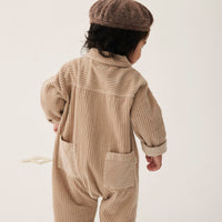 Child wearing a beige ribbed outfit and brown beret on a white background