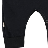 Close-up of a black baby romper with a brand label on a white background