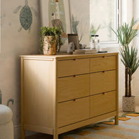 Wooden dresser in a room with turtle-themed wallpaper, rug, and decor items.