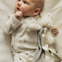 Baby lying on a soft surface holding a blanket and toy