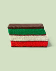 Layered dessert with chocolate, green, white, and red layers on a light green background