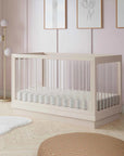 Nursery room with a white crib, light pink walls, and decorative elements.
