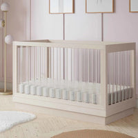 Nursery room with a white crib, light pink walls, and decorative elements.