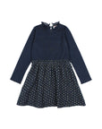 A long-sleeve children's dress in dark navy blue, featuring a ribbed mock neck and upper bodice that transitions into a gathered, flared skirt with a small floral pattern.