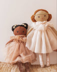 Two dolls in dresses on a textured surface with a neutral background