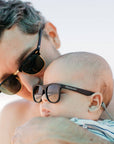 Man and baby wearing sunglasses with a blurred background