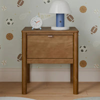 Wooden nightstand with lamp and clock against a wall with sports-themed wallpaper