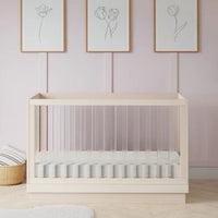 Wooden crib in a room with light pink walls, framed artwork, and decorative items.