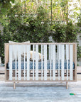 Wooden crib in a nursery with greenery and a rug