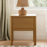Wooden nightstand with a lamp next to a bed in a bedroom.