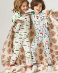 Two children in pajamas with a floral pattern on a plain background