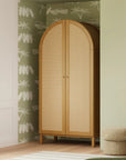 Wooden wardrobe with wicker doors in a room with patterned wallpaper and a small ottoman.