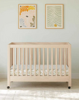 Wooden crib in a room with light-colored walls and a white couch.