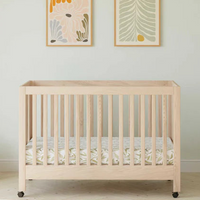 Wooden crib in a room with light-colored walls and a white couch.