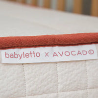 Close-up of a baby crib mattress with 'babyletto x AVOCADO' label.