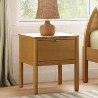 Wooden nightstand with a lamp next to a bed in a bedroom setting