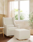 White armchair and ottoman in a bright living room with a window and plants.