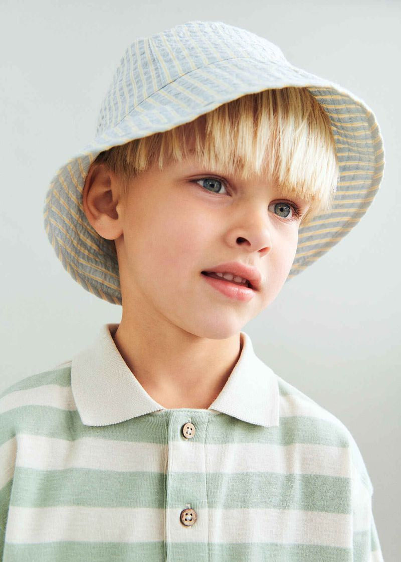 Young boy wearing a striped hat and shirt against a plain background