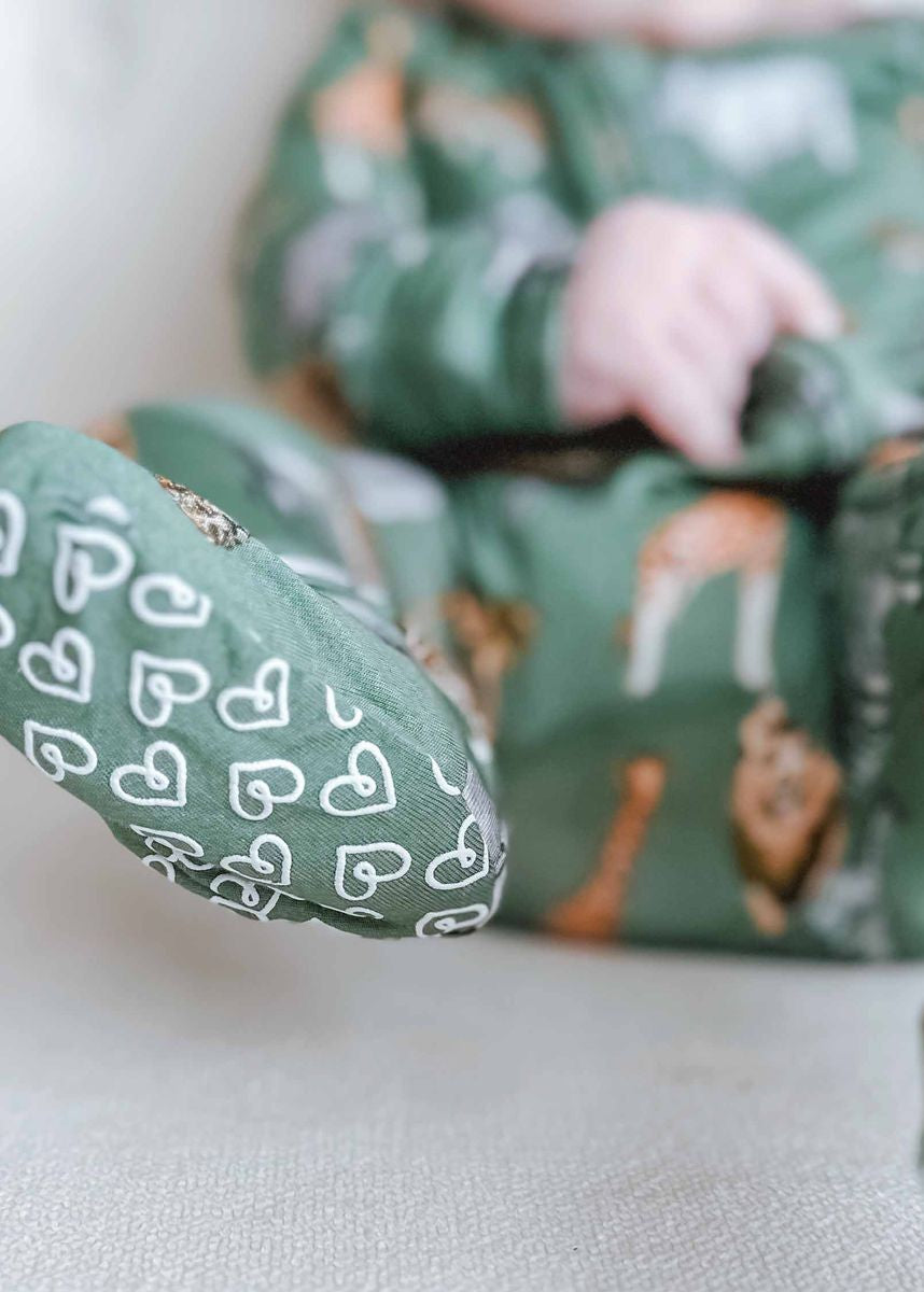 Green fabric with deer pattern and white heart designs on a light background