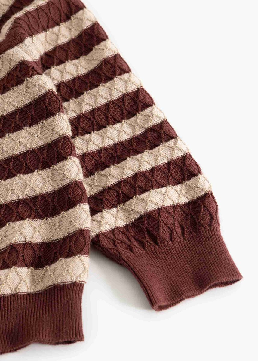 A close-up of a striped knit sweater sleeve with alternating horizontal bands of deep burgundy and warm beige, featuring textured cable-knit and diamond-patterned sections with ribbed cuffs.