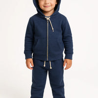 Child wearing a navy blue hoodie and pants set on a white background