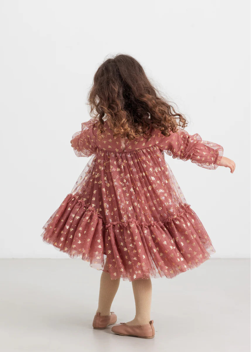Child wearing a pink dress with ruffles on a white background