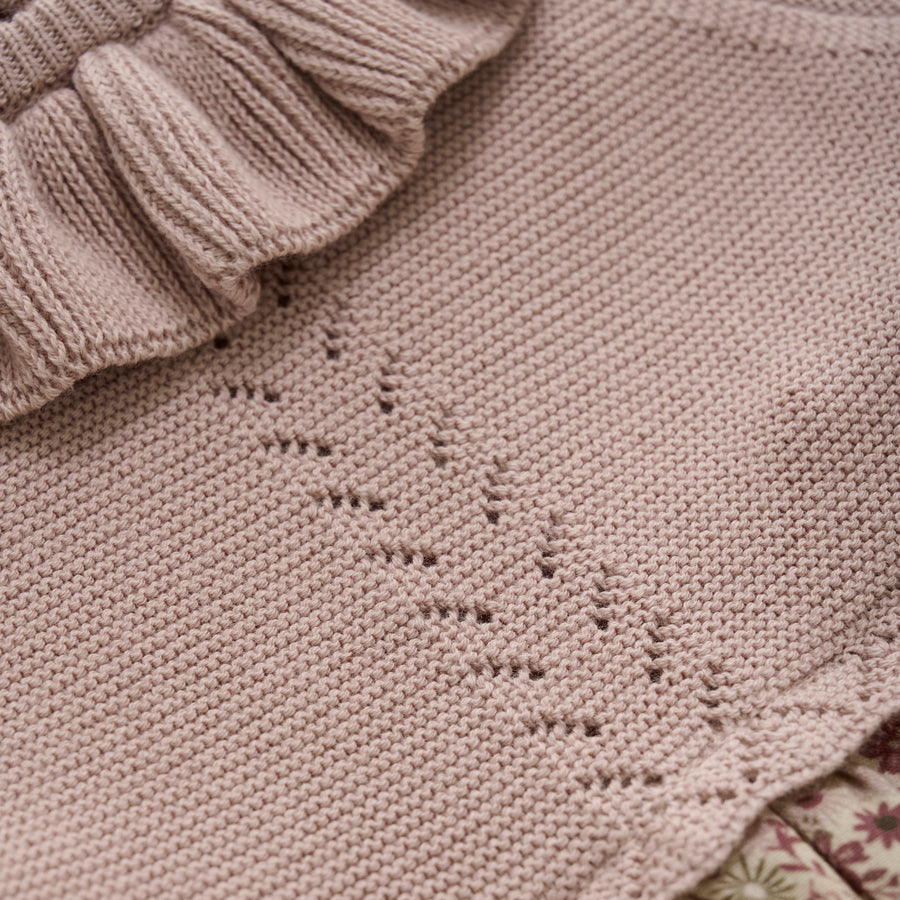 Close-up of a knitted garment with a subtle pattern on beige fabric.