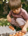 Child with a carton of eggs outdoors