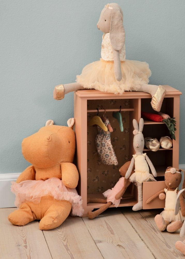 Children's toys and a small wooden cabinet against a light blue wall.