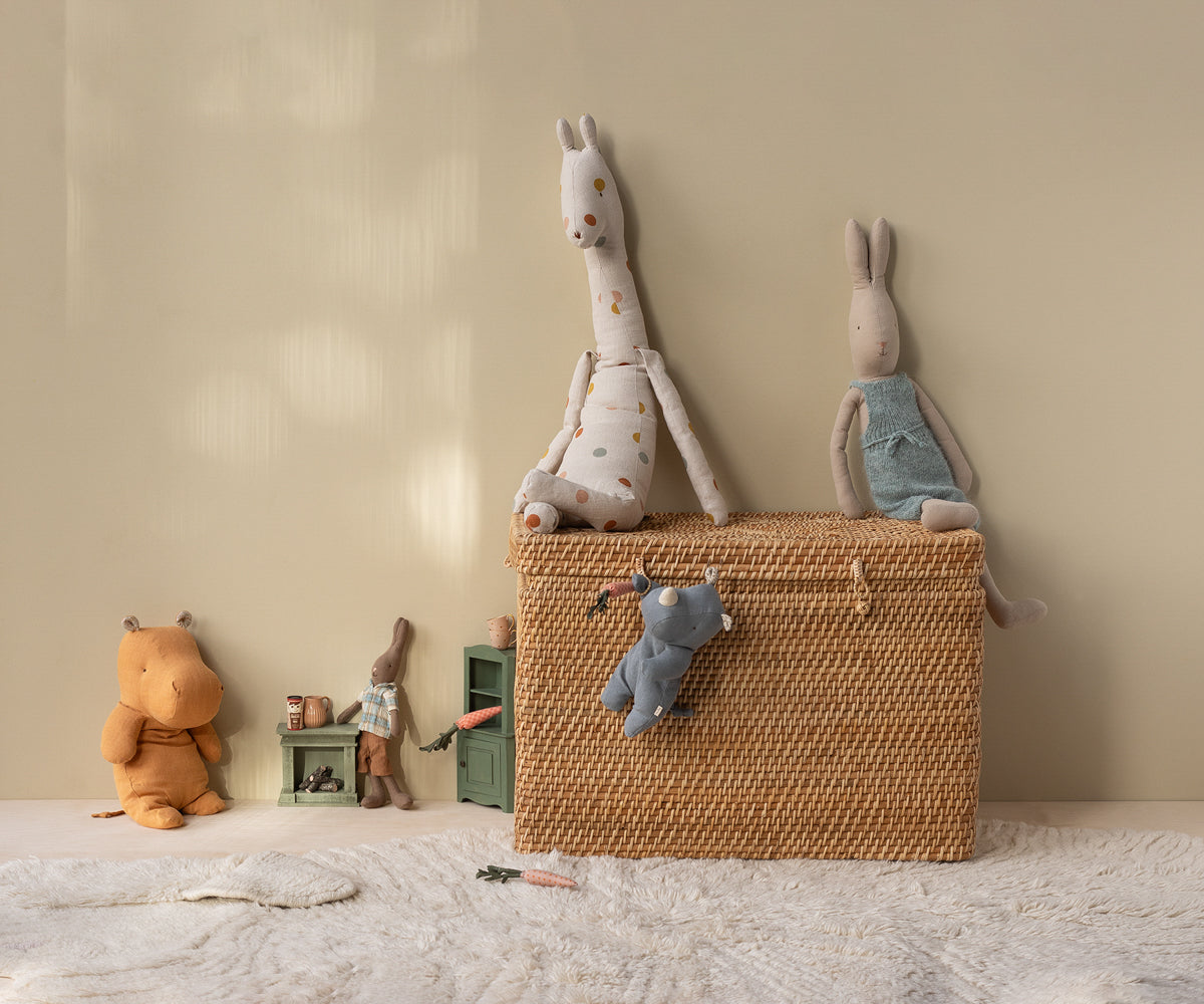 Wicker basket with plush toys on a light-colored floor against a beige wall