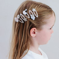 Child with decorative hair clips on a plain background