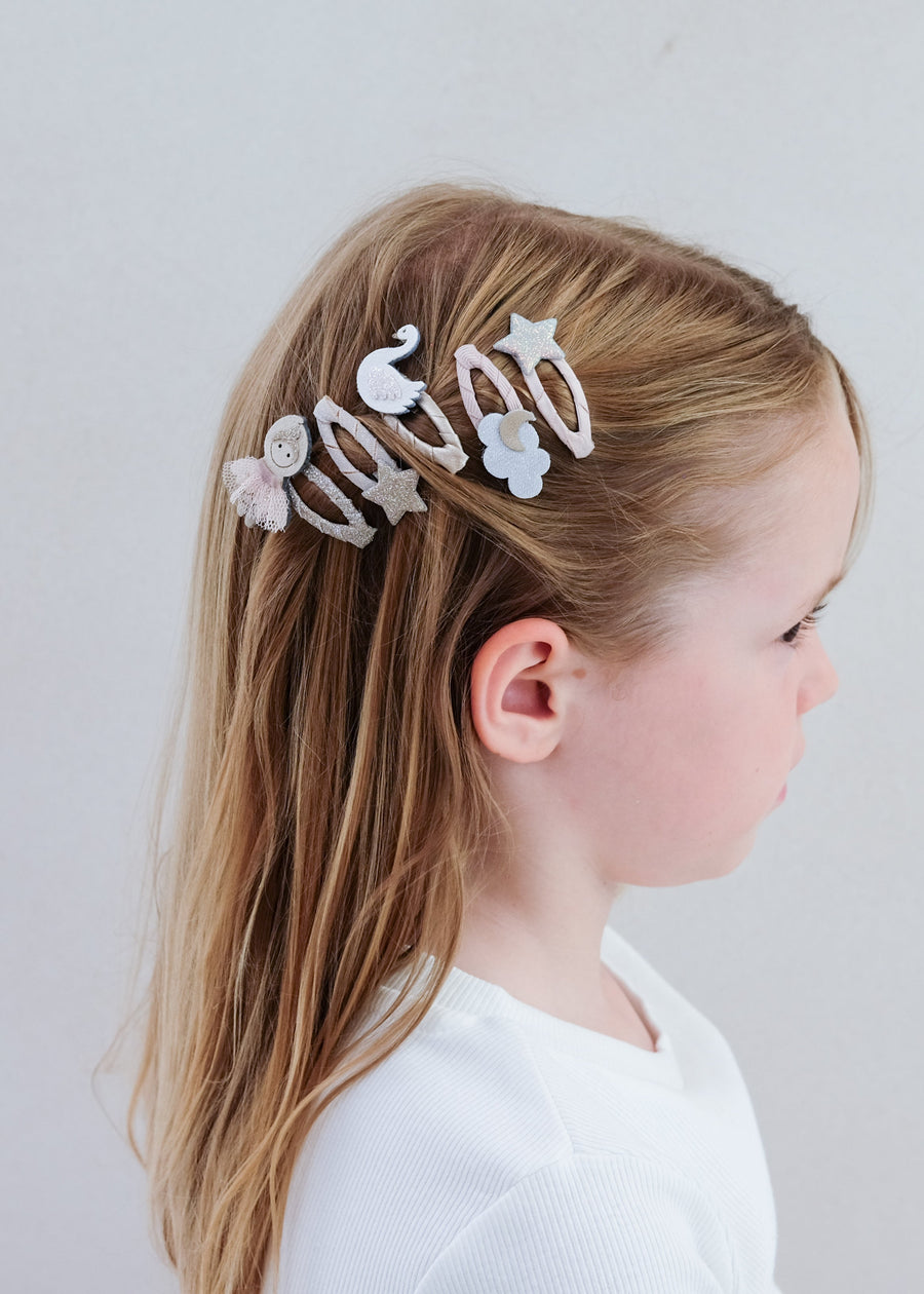Child with decorative hair clips on a plain background