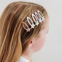 Person with long blonde hair wearing a decorative hair clip on a plain background