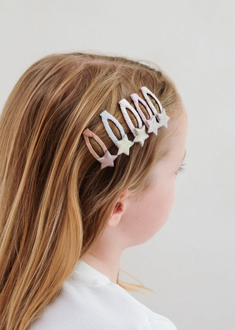 Person with long blonde hair wearing a decorative hair clip on a plain background