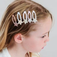 Young girl with decorative hair clips on a plain background