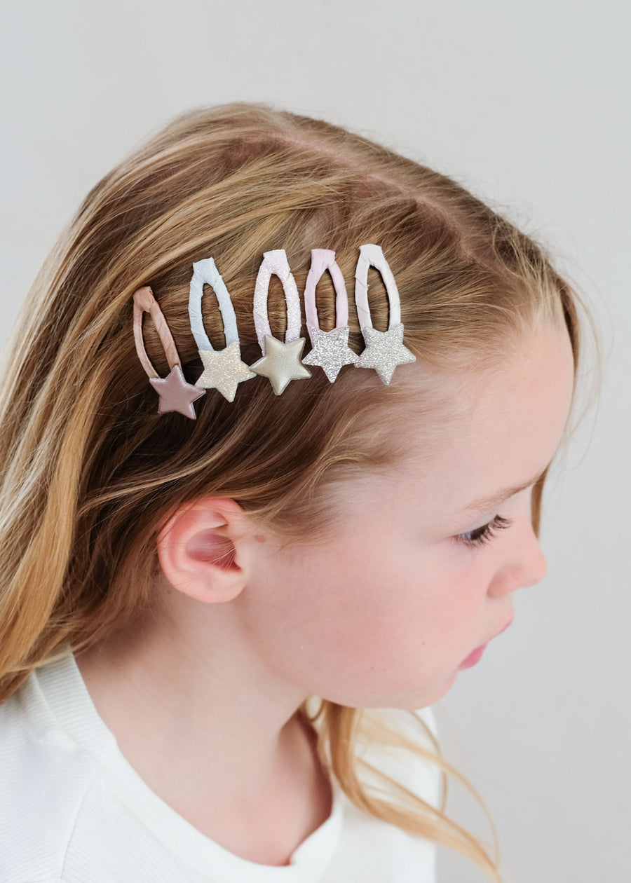 Young girl with decorative hair clips on a plain background