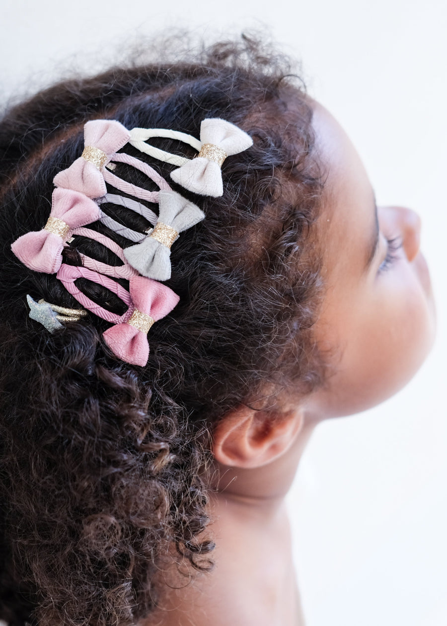 Child with curly hair wearing multiple decorative hair clips on a white background