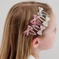 Girl with pastel bow hair clips in her hair on a plain background